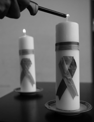 Black-and-white shot of two candles with purple ribbon on their front being lit to symbolise domestic violence awareness