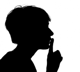 A silhouette of a boy with a finger on his lips in a silencing gesture