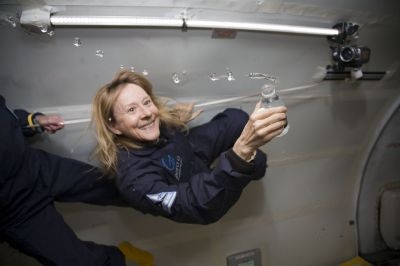 Esther Dyson inside a zero-g stimulator holding an open water-bottle with water bubbles floating out of it
