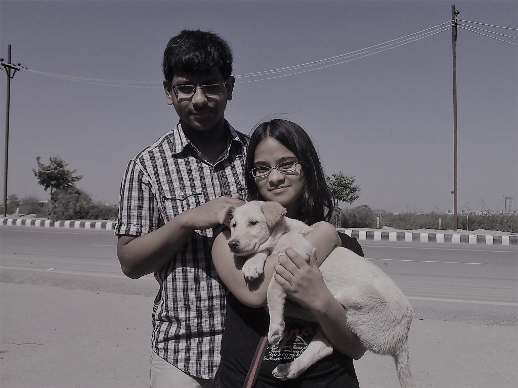 A sepia-toned picture of Swara and her twin brother holding Dobby as a puppy in 2011